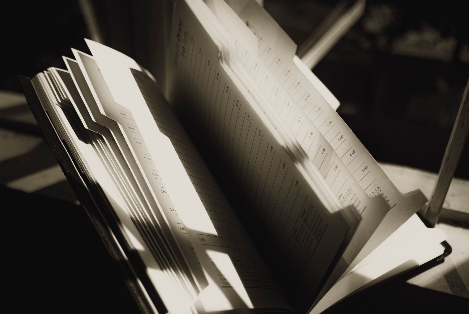 Shiny pages of agenda with lines and shadows on sunny day on blurred background