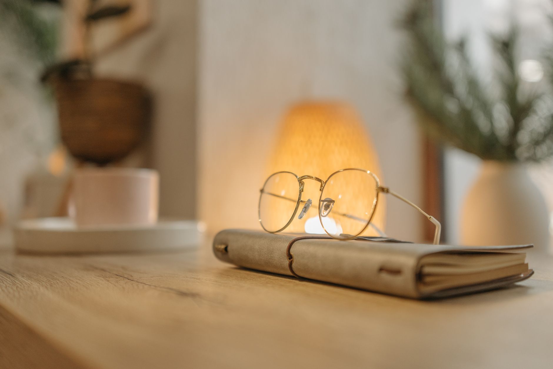 Warm, inviting home office scene with journal and eyeglasses on wooden table.