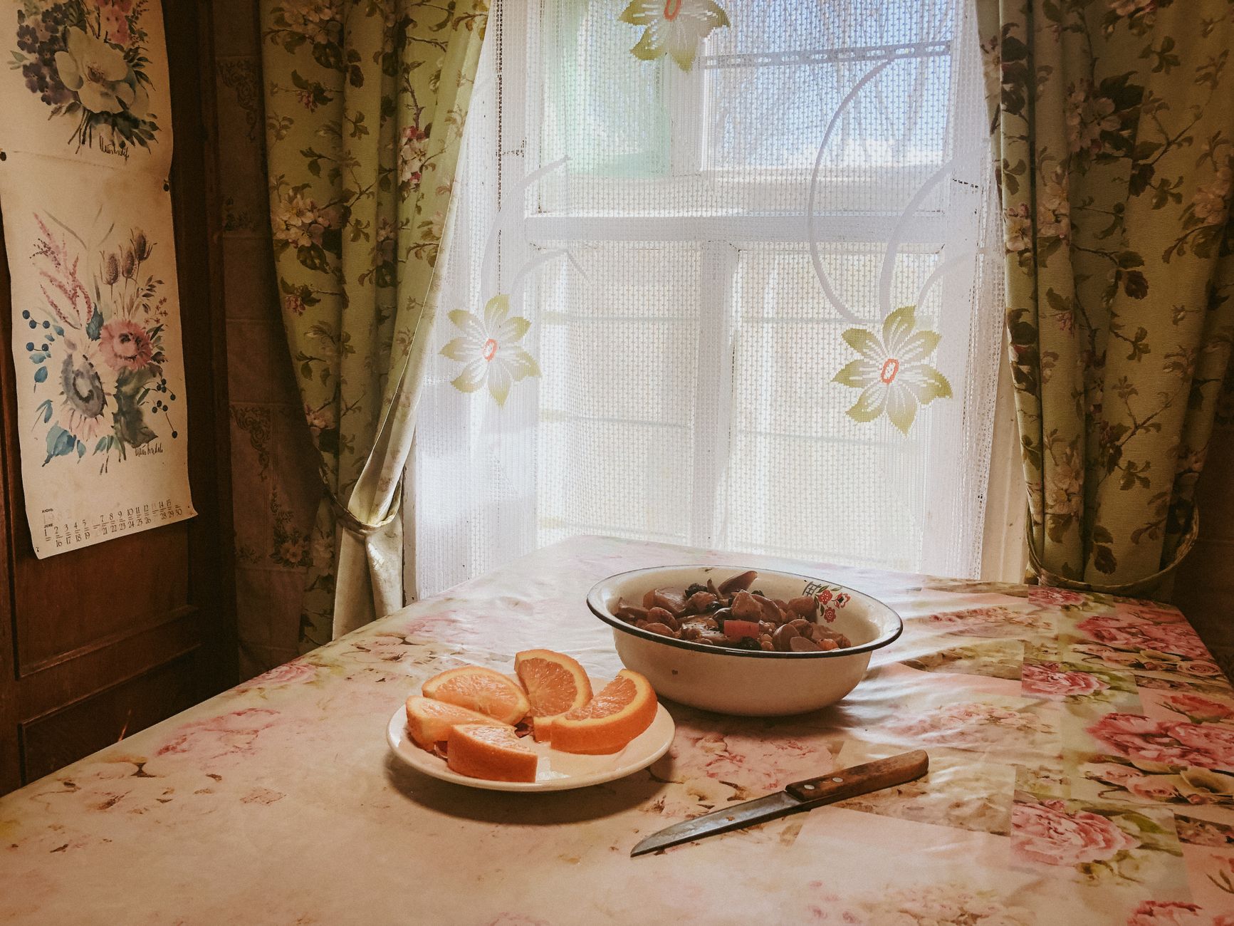 A quiet kitchen table in soft morning light, with lace curtains casting shadows.
