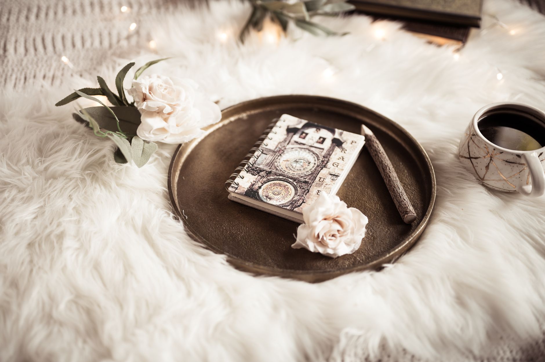Aesthetic still life with a notebook, coffee cup, and flowers on faux fur, creating a cozy ambiance.