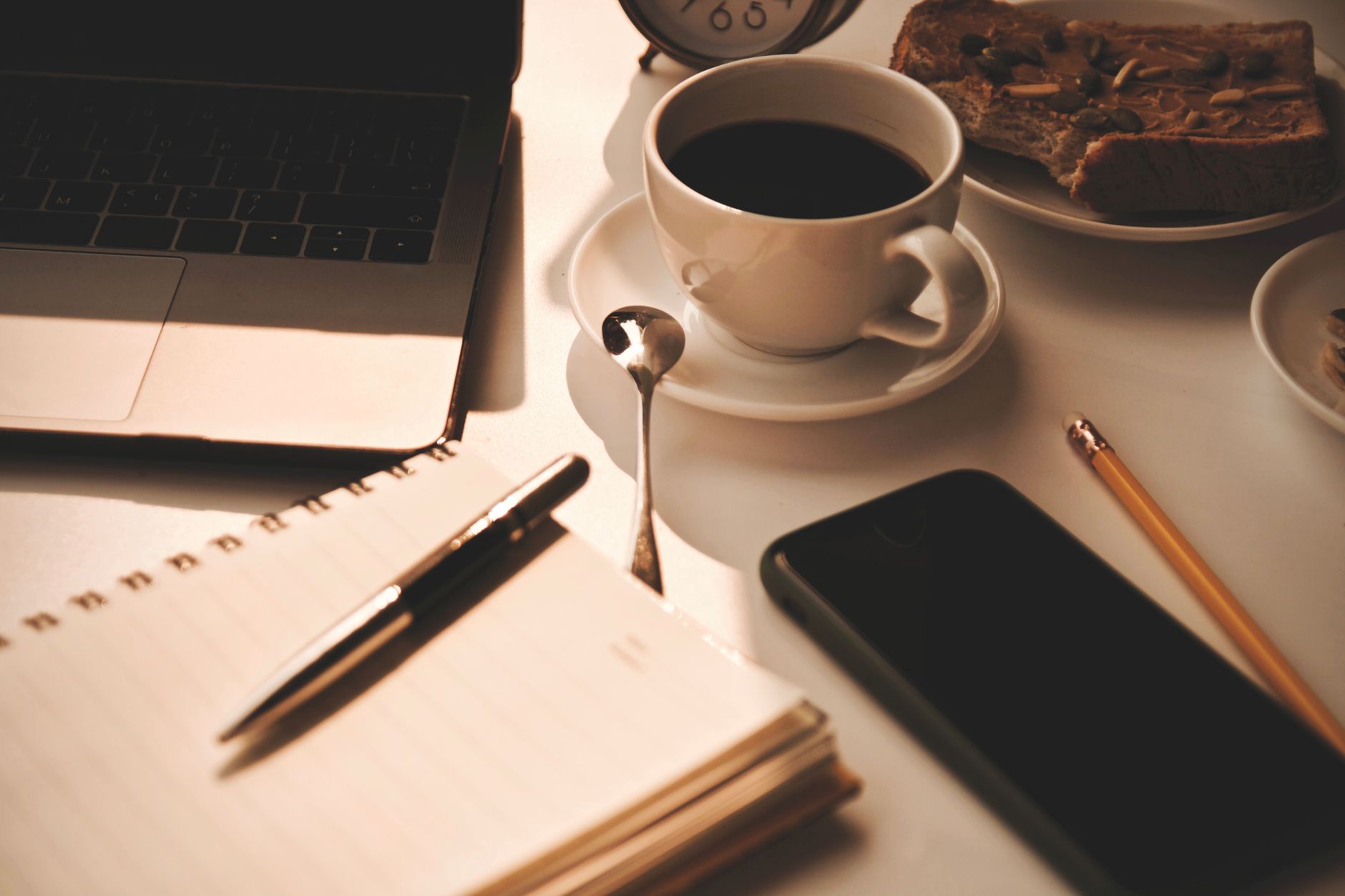 Warm and inviting workspace setup with coffee, notebook, and snacks, perfect for productivity.