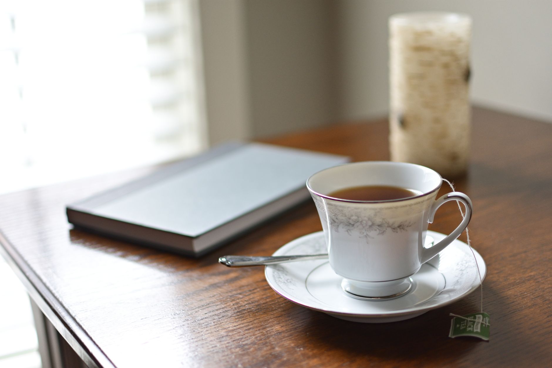 A serene morning scene with a teacup, journal, and candle on a wooden table, perfect for relaxation and reading.