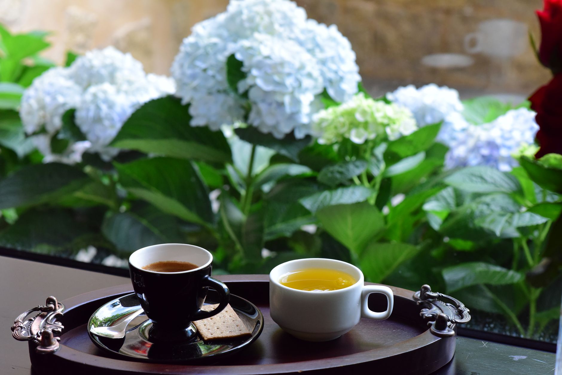 Elegant coffee and tea setup with outdoor hydrangeas in background.