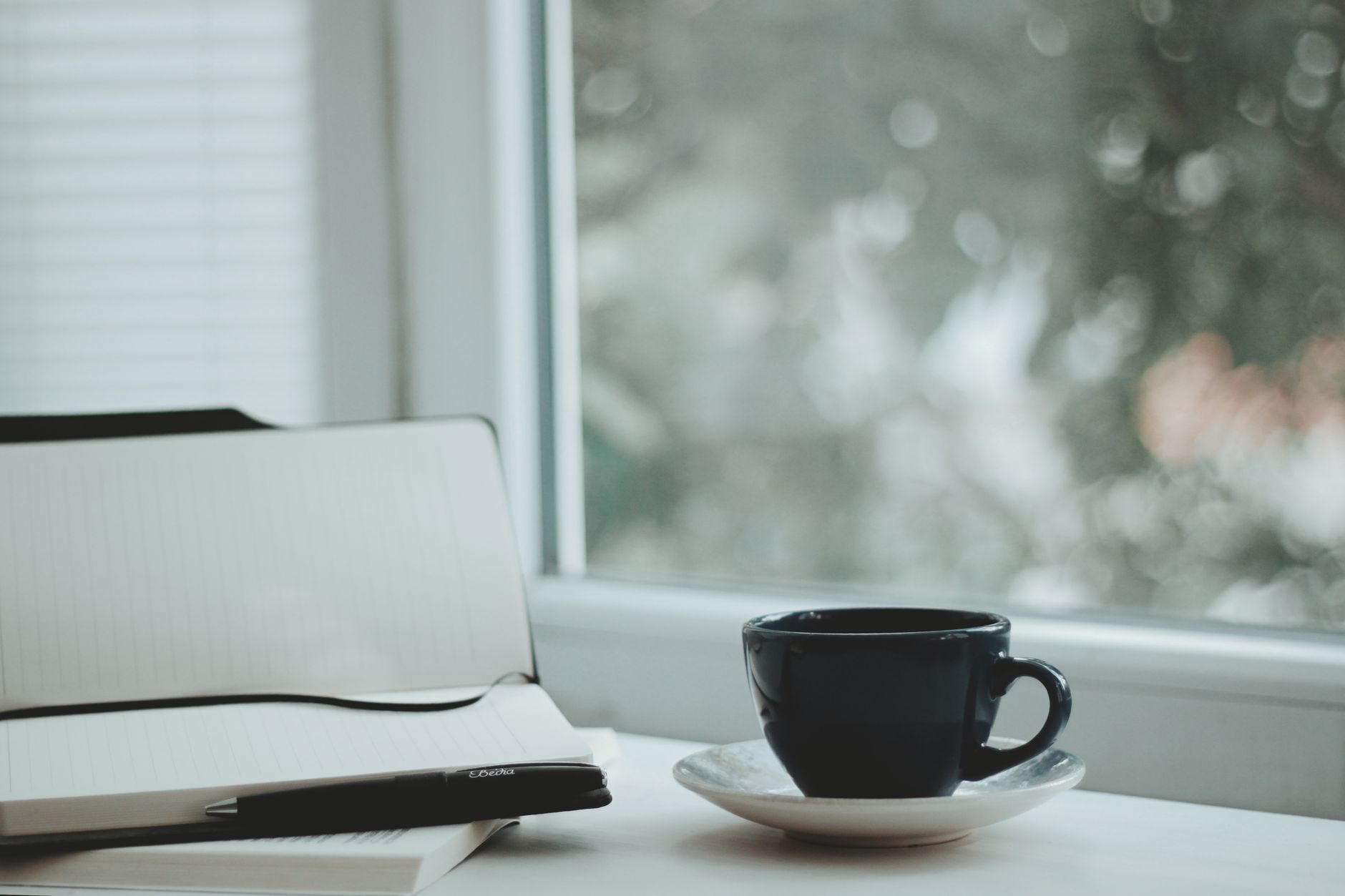 A serene scene with a coffee cup and notebook by a window, perfect for calm mornings.