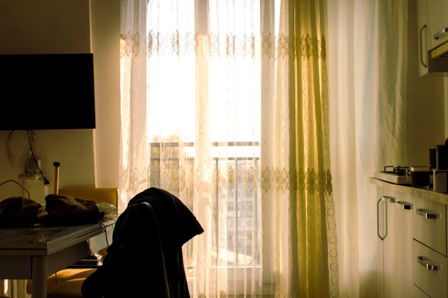 Warm, inviting apartment with sunlight streaming through sheer curtains, highlighting a cozy indoor atmosphere.