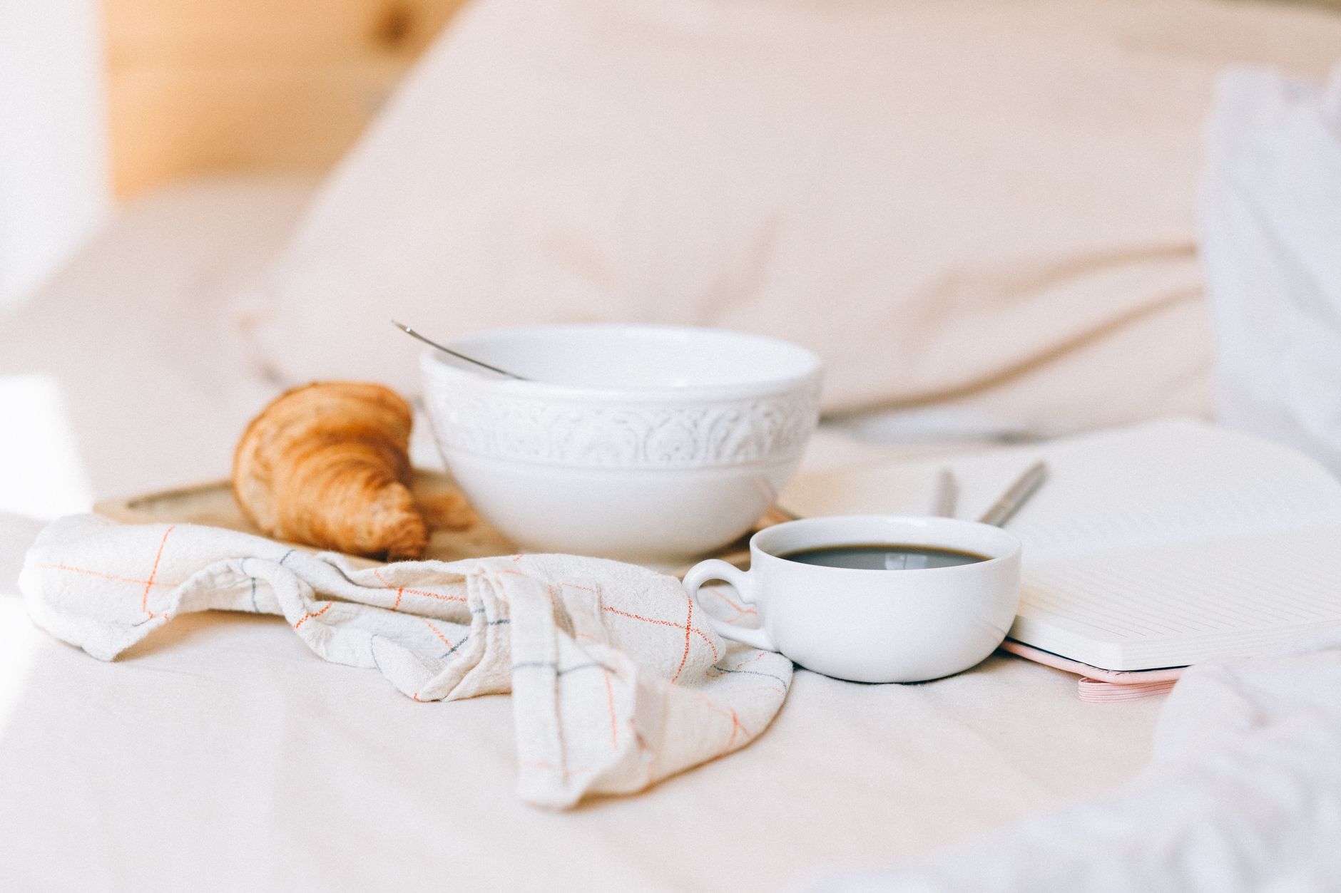 Start your day with a delicious breakfast in bed, featuring a croissant and coffee.