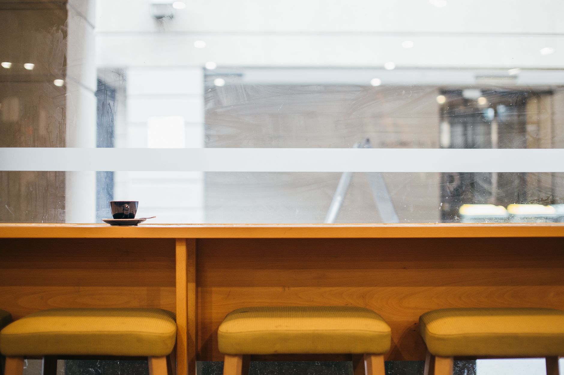 Quiet coffee shop with a retro feel, featuring empty chairs and a coffee cup by the window.