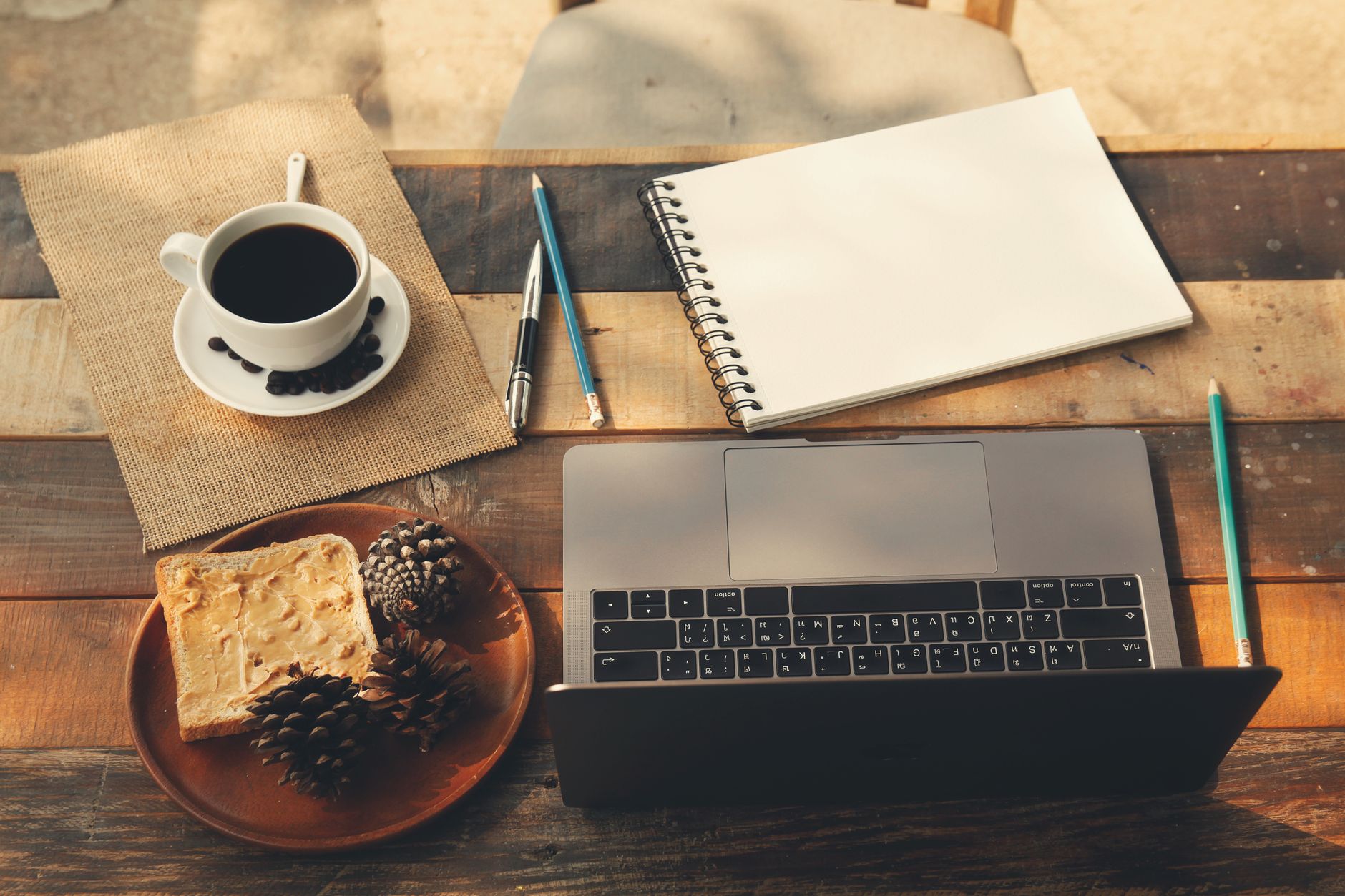 A warm, inviting home office workspace with a coffee cup, laptop, and notepad on a wooden table.