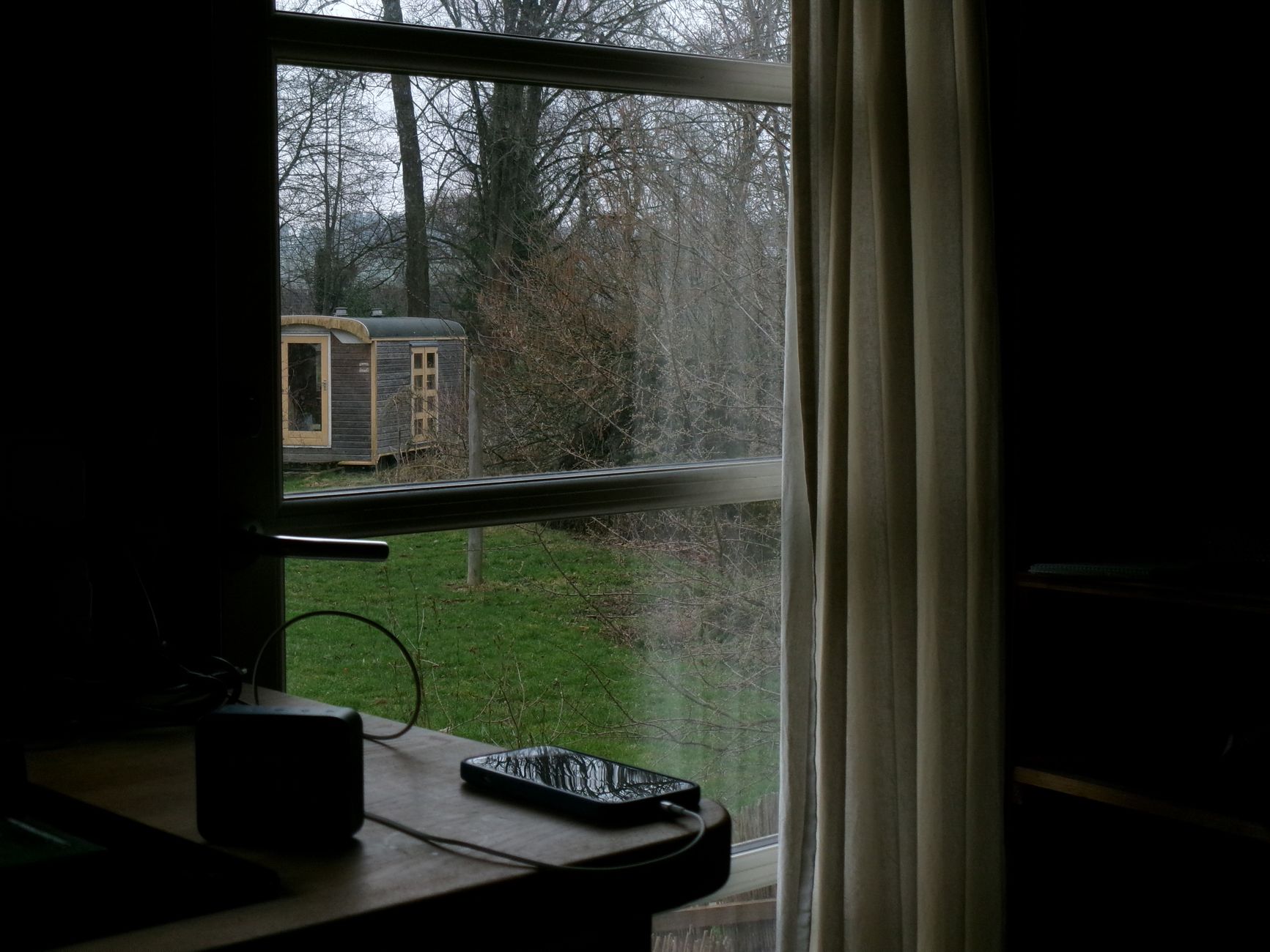 Glimpse of a rustic cabin outside a window with a serene nature view.