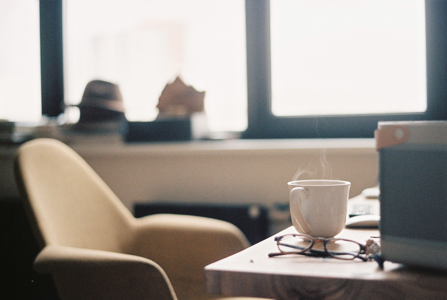 Warm indoor setting featuring a steaming cup of coffee, inviting chair, and soft lighting for relaxation.