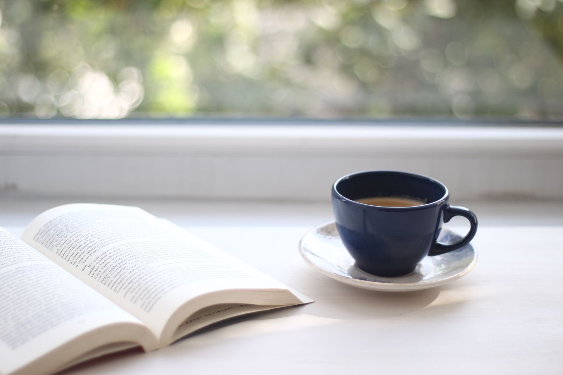 A serene setting of a book and coffee cup by a sunlit window, perfect for relaxation.